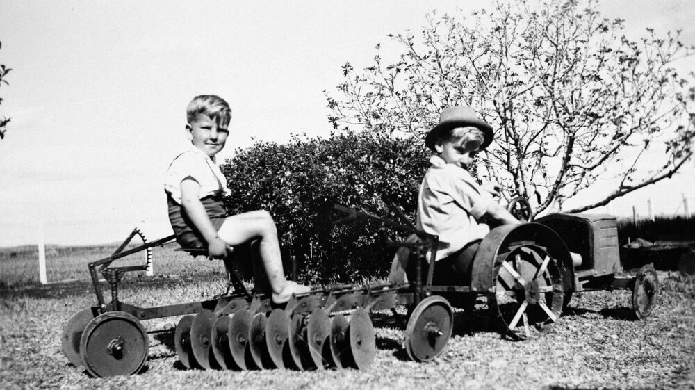 Two boys on a toy tractor, unknown location, no date