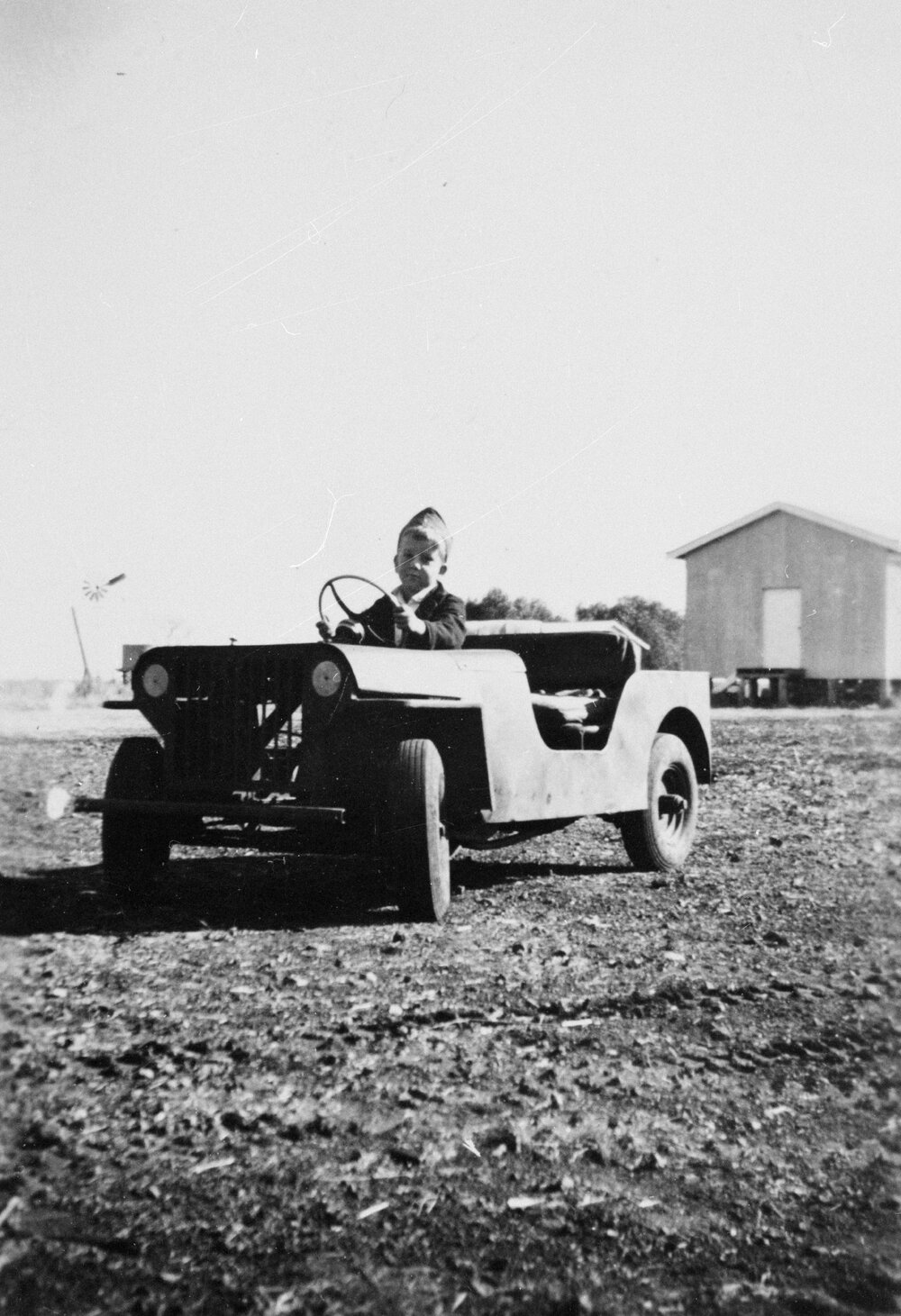 Boy in a small car, unknown location, no date